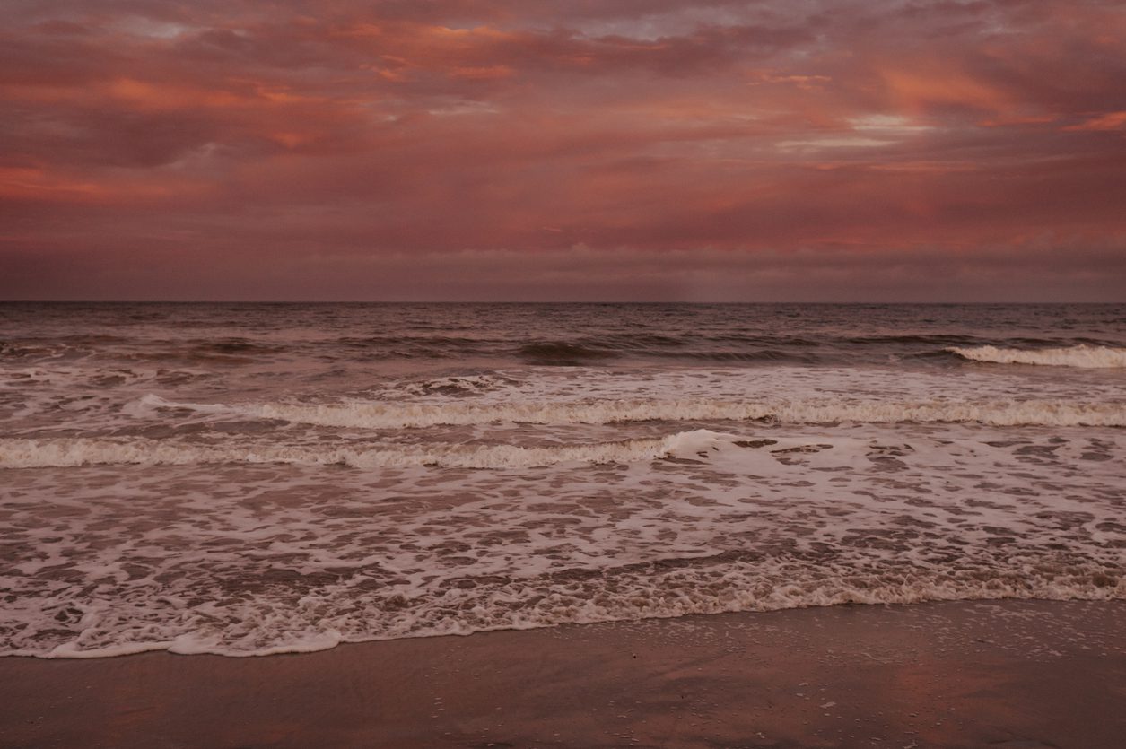 pink sunset on beach with waves in Charleston, SC